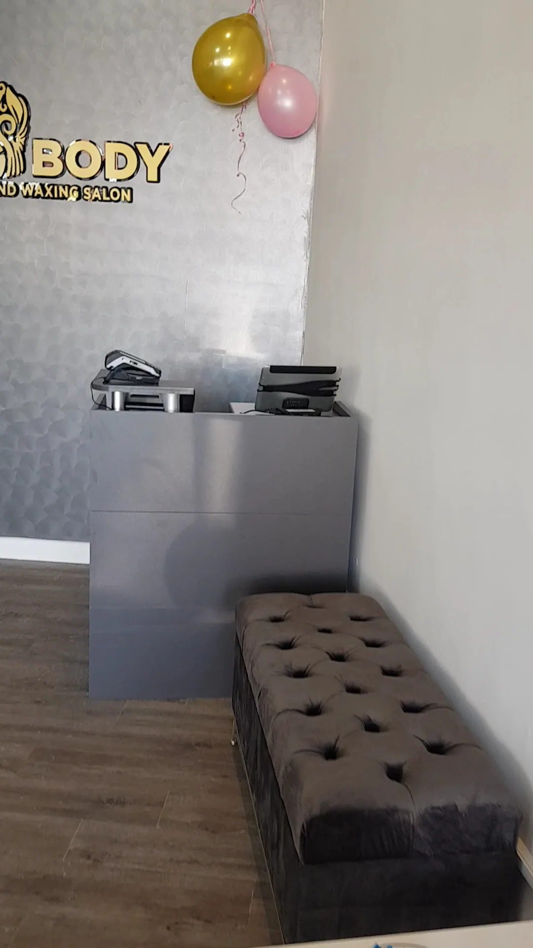 Silk Body reception area with gold logo wall and tufted ottoman
