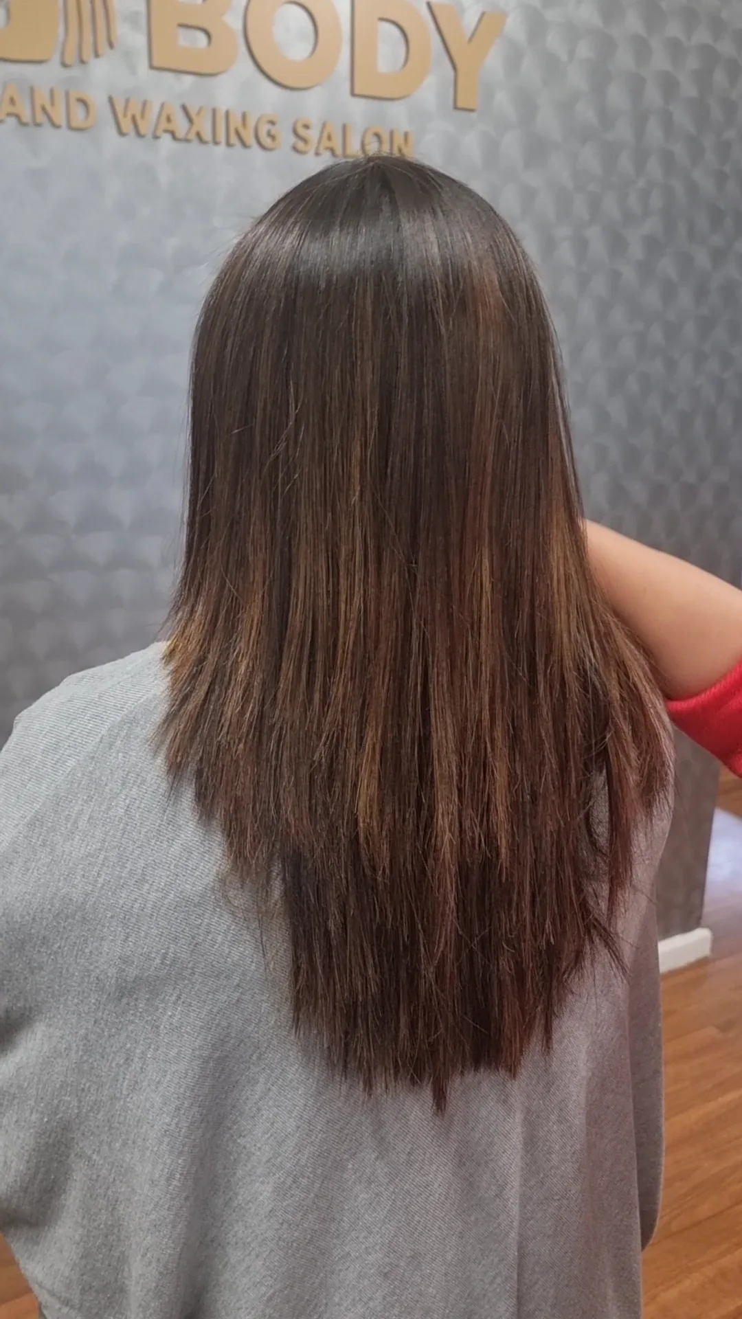 Glossy straightened hair finished at Silk Body, rear view